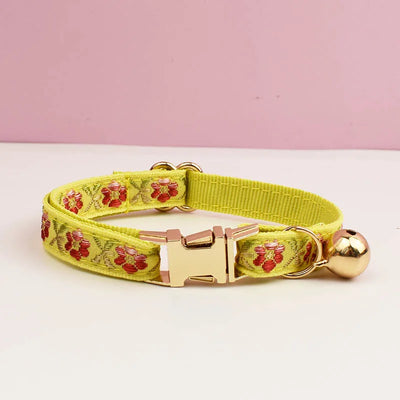 Yellow dog collar with floral pattern and gold buckle on a pink background